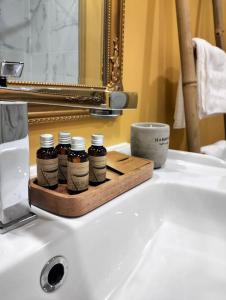 ein Waschbecken im Bad mit 4 Flaschen auf einem Holztablett in der Unterkunft Altstadt House in Braşov