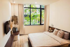 a bedroom with a bed and a large window at Areca Boutique Apartments Hanoi in Hanoi