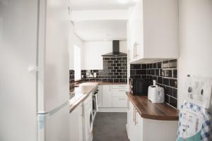 a kitchen with white cabinets and black tiles at Leicester Park House in Leicester