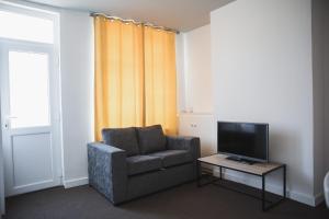 a living room with a chair and a television at Leicester Park House in Leicester