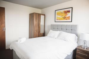 ein Schlafzimmer mit einem weißen Bett und einem Bild an der Wand in der Unterkunft Leicester Park House in Leicester