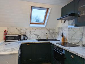 una cocina con armarios verdes y una ventana en Morrigan 7-Hot Tub-Pet Friendly-Boutique-Perthshire-Families en Perth