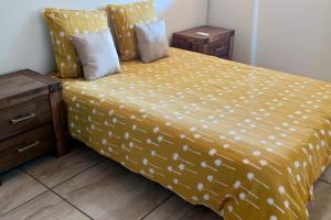 ein Schlafzimmer mit einem Bett mit gelber Decke in der Unterkunft Les lataniers 1 - Vue sur mer in Saint-Pierre