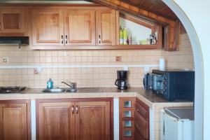 una cucina con armadi in legno, lavandino e forno a microonde di Les lataniers 1 - Vue sur mer a Saint-Pierre
