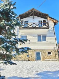 a large white building with a balcony in the snow at Carpathian manor in Yaremche