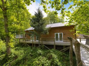 um chalé de madeira na floresta com um deque de madeira em 3 Bed in Chulmleigh 87779 em Eggesford