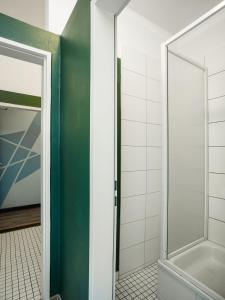 uma casa de banho com um chuveiro e uma porta de vidro em EastSeven Berlin Hostel em Berlim