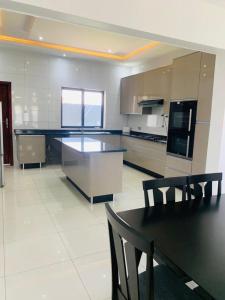 uma grande cozinha com uma mesa preta e cadeiras em Executive 4 bedroom house with 4 beds . em Lusaka
