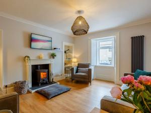 a living room with a fireplace and a chair at 3 Bed in Lossiemouth 87871 in Lossiemouth