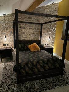 a black bed in a room with a stone wall at The Cottage, Everards Farm in Chewton Mendip
