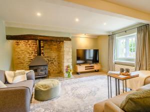 a living room with a stone fireplace and a television at 3 Bed in Beaminster 87914 in South Perrott