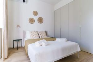 Modern & Bright Faro Mercado Apt 12 في فارو: غرفة نوم بيضاء بسريرين عليها مناشف