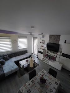 Stan na dan Apartman KRISFIL Prnjavor في Prnjavor: غرفة معيشة مع أريكة وتلفزيون