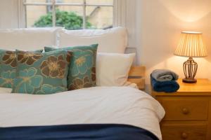 a bed with pillows and a lamp on a night stand at Stunning Georgian Spacious Apartment Central Bath in Bath