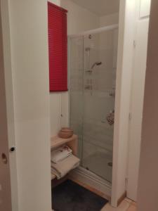 baño con ducha de cristal y ventana roja en La Frênaie, en Saint-Cyr-sur-le-Rhône
