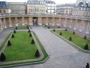 un grand bâtiment avec une cour entourée de gazon et de buissons dans l'établissement Le Marais, fantastic view on Archives Nationales, à Paris