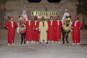 un groupe de personnes habillées en rouge debout à côté des chevaux dans l'établissement Ksar Elkabbaba Kasbah & SPA, à Skoura