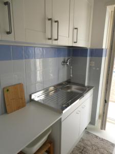 una cucina con lavandino e armadietti bianchi di Luminoso Appartamento A 80 Metri dal Mare a Terracina