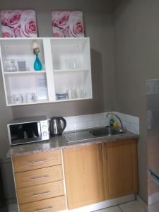 - un comptoir de cuisine avec évier et four micro-ondes dans l'établissement The Westpoint -Modern ,secure apartment, à Roodepoort