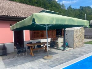 ein großer grüner Regenschirm neben einem Pool in der Unterkunft Villa Ruzmarin in Zolaći