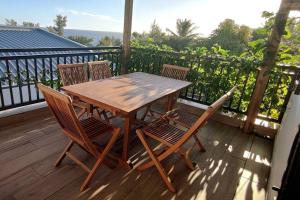 una mesa de madera y sillas en una terraza en Les lataniers 2 - Vue sur mer, en Saint-Pierre