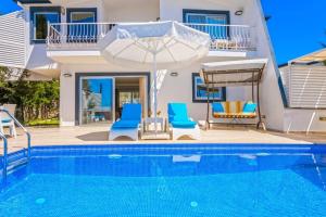 a swimming pool with two chairs and an umbrella next to a house at Villa Mono / Kalkan in Kas