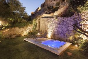 ラグーザにあるLocanda Don Serafino Historical Boutique Hotelの石壁の隣の庭にホットタブがあります。