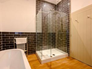 a bathroom with a tub and a shower with black tiles at 3 Bed in Buttermere 88773 in Buttermere