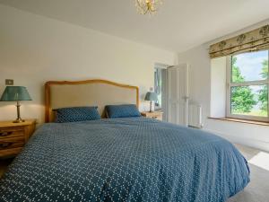 1 dormitorio con 1 cama con edredón azul y ventana en 3 bed property in Cunsey Lake District 88769, en Far Sawrey