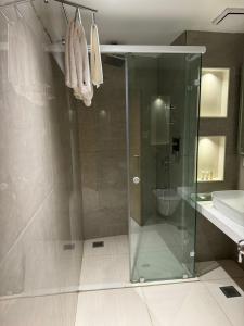 W łazience znajduje się szklana kabina prysznicowa i umywalka. w obiekcie Chinmay Hotel & Resort w mieście Lucknow