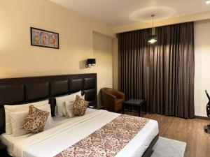 Chinmay Hotel & Resort في لاكناو: غرفه فندقيه بسرير وكرسي