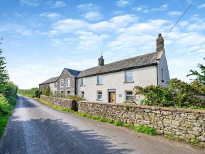 a white house on a stone wall on a road at 5 Bed in Bassenthwaite 89496 in Torpenhow