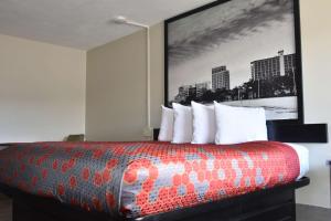 a hotel room with a bed with a large picture on the wall at Super 8 by Wyndham Biloxi in Biloxi +37 photos