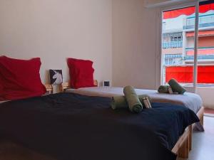um quarto com 2 camas com almofadas vermelhas e uma janela em 100m des plages centre Antibes em Antibes