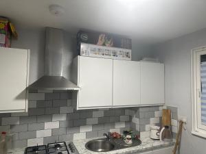 a kitchen with white cabinets and a sink at Feel at home in Abbey Wood