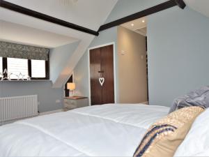 パラクームにある1 Bed in Exmoor National Park 89766の白いベッドと木製のドアが備わるベッドルーム1室が備わります。