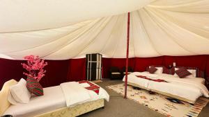 two beds in a room with a tent at Al Salam Desert Camp Bidiya in Badīyah