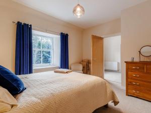 4 Bed in Pitlochry 89750 في Tummel Bridge: غرفة نوم بسرير ونافذة ذات ستائر زرقاء