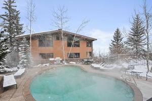 a swimming pool in front of a house in the snow at Aspenwood One Bedroom J3 in Snowmass Village