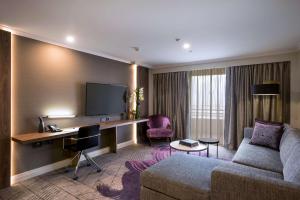 a hotel room with a couch and a desk with a computer at Rydges South Bank Brisbane in Brisbane