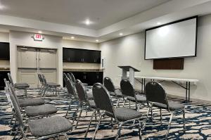Comfort Suites Oil Center في لافاييت: قاعة اجتماعات مع كراسي وشاشة عرض