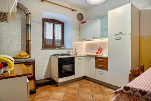 uma cozinha com armários brancos e um forno com placa de fogão em Beb chalet bella vita Trento em Vignola