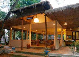 un bâtiment avec un toit de paille et un restaurant dans l'établissement Raindrops Resorts Wayanad Kerala, à Sultan Bathery