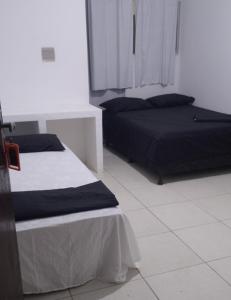 a bedroom with two beds and a white floor at Pousada Pé na Areia in São José da Coroa Grande