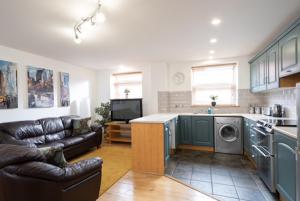 a living room with a couch and a kitchen at Belfast 2 Bed Apartment in Belfast