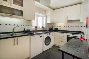 a white kitchen with a sink and a dishwasher at Boho Chic Beach Duplex in Sesimbra