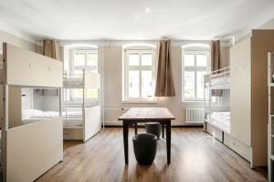 a room with a table and bunk beds at EastSeven Berlin Hostel in Berlin