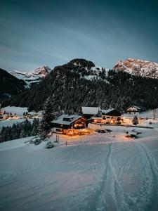 a lodge in the snow with snow covered mountains at Mountain Chalet Pra Ronch in Selva di Val Gardena