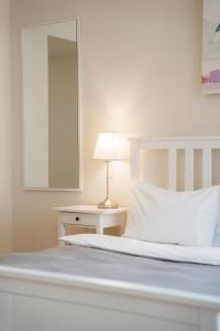 - une chambre dotée d'un lit blanc avec une lampe et un miroir dans l'établissement Danylo Inn, à Lviv