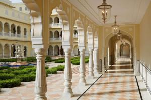 Hyatt Regency Jaipur Mansarovar في جايبور: ممر في قصر وبه اعمدة ونباتات
